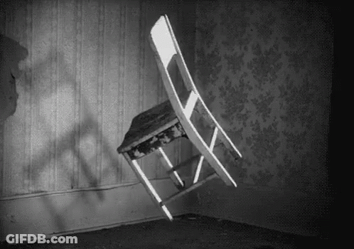 A Black And White Photo Of A Chair That Is Flying Through The Air In A Room . GIF