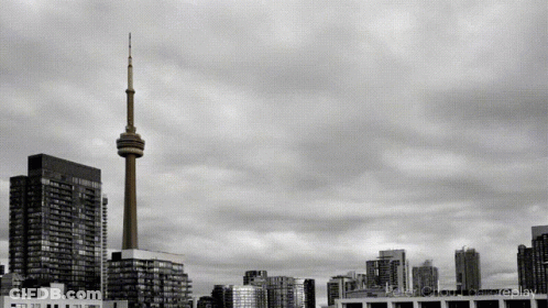 A Black And White Photo Of A City Skyline With A Tower In The Middle GIF