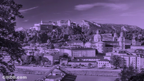 A Black And White Photo Of A City With A Castle On Top Of A Hill GIF