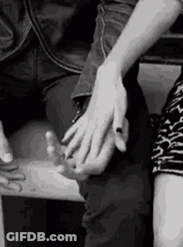 A Black And White Photo Of A Couple Holding Hands . GIF