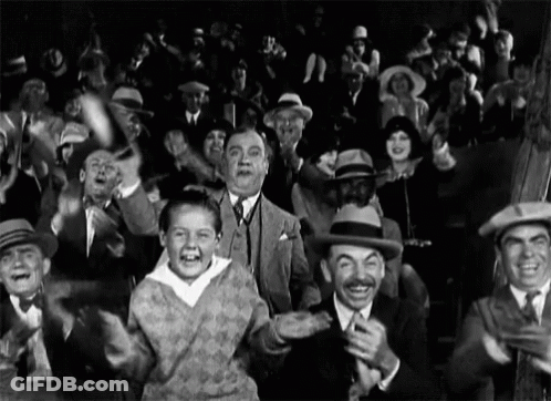 A Black And White Photo Of A Crowd Of People GIF