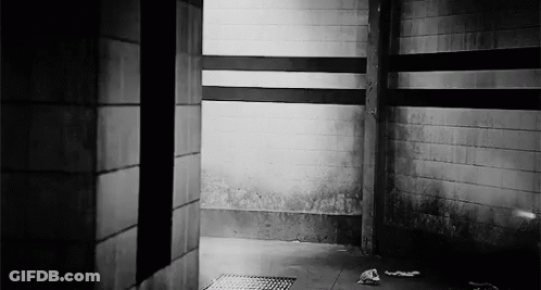 A Black And White Photo Of A Dark Room With A Brick Wall And A Drain . GIF