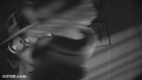 A Black And White Photo Of A Doll Wearing A Hat GIF