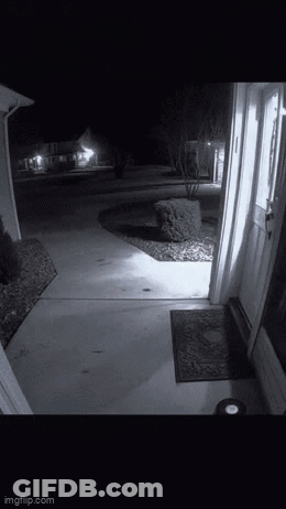 A Black And White Photo Of A Doorway At Night With A Light On . GIF