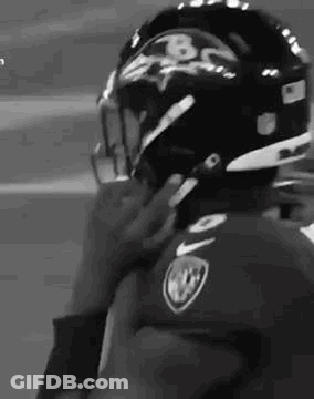 A Black And White Photo Of A Football Player Putting On His Helmet . GIF