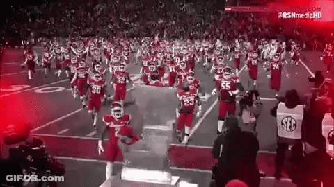 A Black And White Photo Of A Football Team Running On The Field GIF