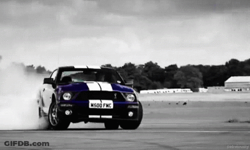 A Black And White Photo Of A Ford Mustang Drifting On A Track GIF