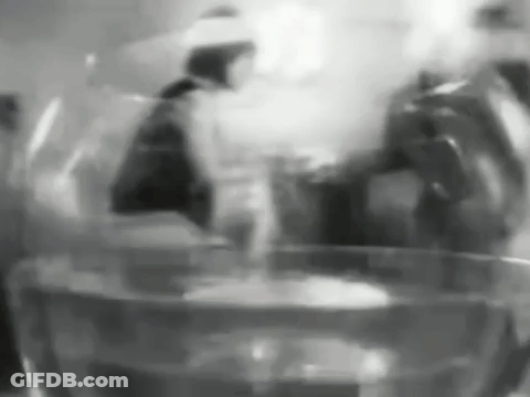 A Black And White Photo Of A Glass Of Water With A Person In The Background . GIF