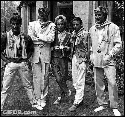 A Black And White Photo Of A Group Of Men Standing In Front Of A Building . GIF
