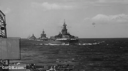 A Black And White Photo Of A Group Of Military Ships In The Ocean GIF