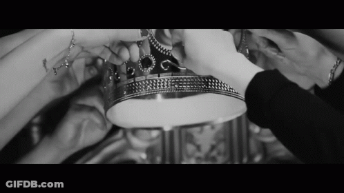 A Black And White Photo Of A Group Of People Holding A Silver Crown GIF