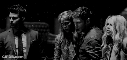 A Black And White Photo Of A Group Of People Standing Next To Each Other In A Dark Room . GIF