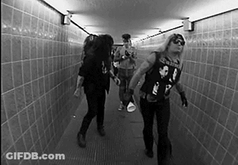 A Black And White Photo Of A Group Of People Walking In A Tunnel . GIF