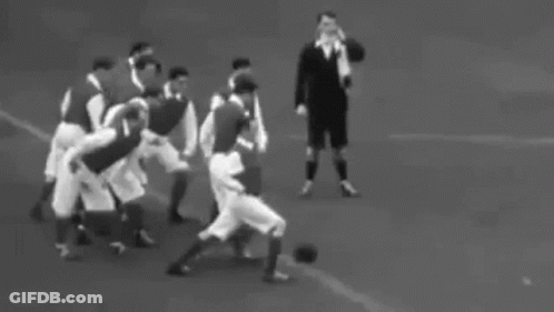 A Black And White Photo Of A Group Of People Walking On A Field . GIF