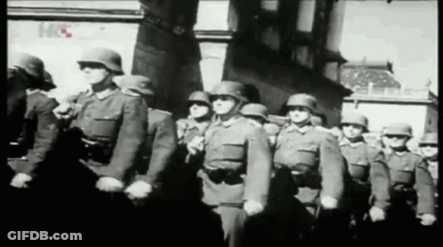 A Black And White Photo Of A Group Of Soldiers Marching In A Line GIF