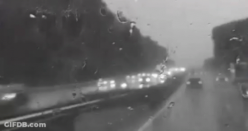 A Black And White Photo Of A Highway Covered In Rain . GIF