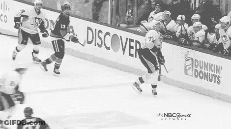 A Black And White Photo Of A Hockey Game With Dunkin Donuts Advertisements On The Sidelines . GIF