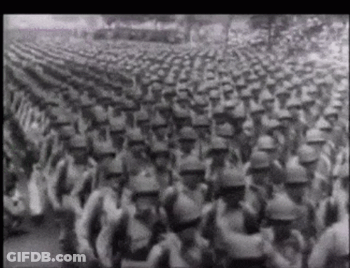 A Black And White Photo Of A Large Army Marching GIF