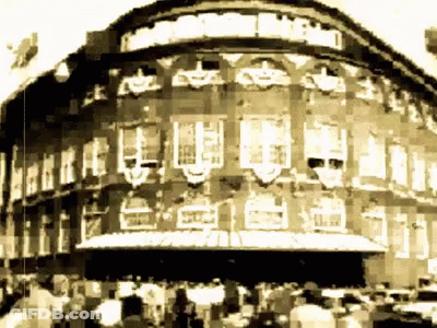 A Black And White Photo Of A Large Building With A Sign That Says ' Theatre ' On It GIF