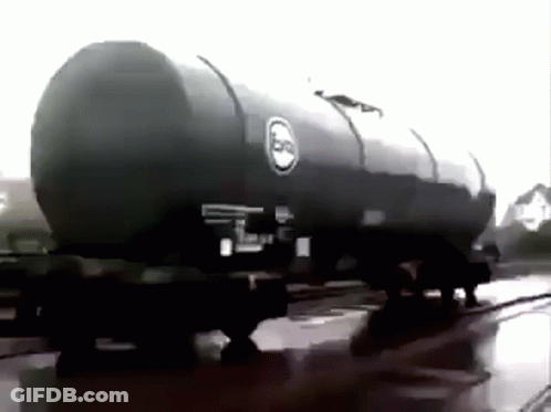 A Black And White Photo Of A Large Oil Tank On A Train Track . GIF