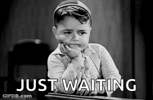 A Black And White Photo Of A Little Boy Sitting At A Desk With His Hand On His Chin And The Words `` Just Waiting '' . GIF