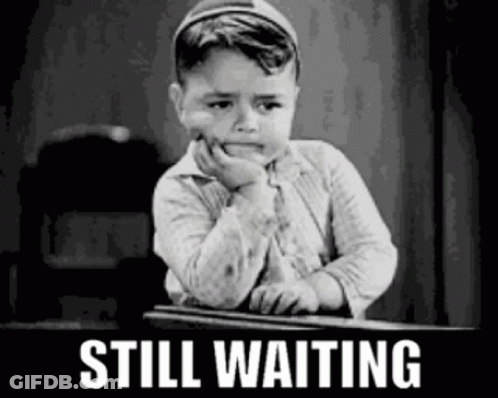 A Black And White Photo Of A Little Boy Sitting At A Desk With The Words `` Still Waiting '' Written Above Him . GIF