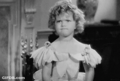 A Black And White Photo Of A Little Girl In A Dress Making A Funny Face . GIF