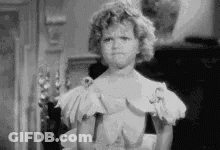 A Black And White Photo Of A Little Girl In A White Dress Making A Funny Face . GIF