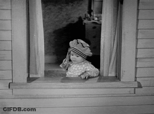 A Black And White Photo Of A Little Girl Looking Out A Window GIF