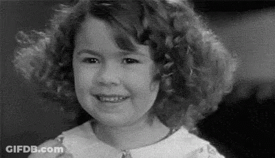 A Black And White Photo Of A Little Girl Smiling . GIF