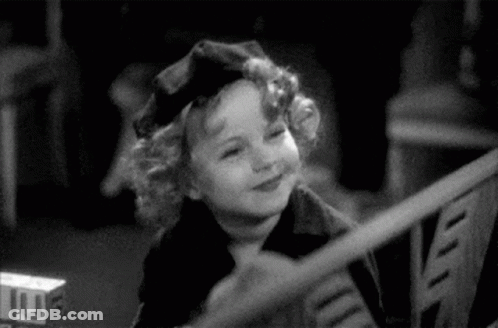 A Black And White Photo Of A Little Girl Wearing A Hat . GIF