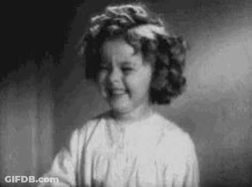 A Black And White Photo Of A Little Girl With Curly Hair Smiling . GIF