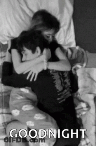 A Black And White Photo Of A Man And A Woman Hugging Each Other In Bed . GIF