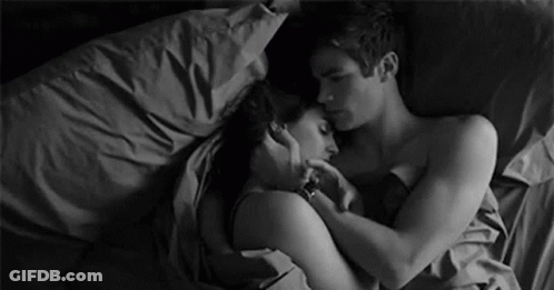 A Black And White Photo Of A Man And A Woman Hugging Each Other In Bed . GIF