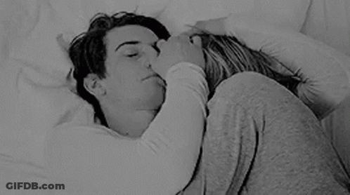 A Black And White Photo Of A Man And A Woman Hugging Each Other In Bed . GIF