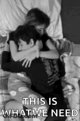 A Black And White Photo Of A Man And A Woman Hugging Each Other On A Bed . GIF