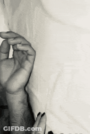 A Black And White Photo Of A Man And A Woman 'S Hands On A Bed . GIF