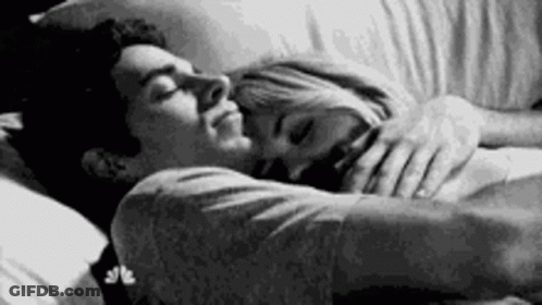 A Black And White Photo Of A Man And A Woman Sleeping In Bed . GIF