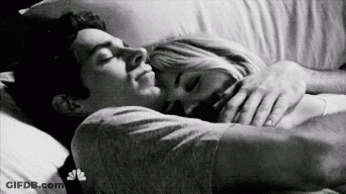 A Black And White Photo Of A Man And A Woman Sleeping In Bed . GIF