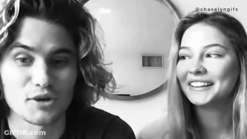 A Black And White Photo Of A Man And A Woman Smiling At Each Other . GIF