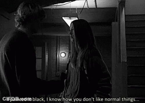 A Black And White Photo Of A Man And A Woman Standing Next To Each Other In A Dark Room . GIF
