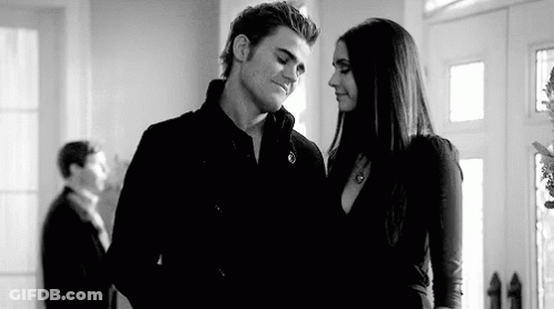 A Black And White Photo Of A Man And A Woman Standing Next To Each Other In A Room . GIF