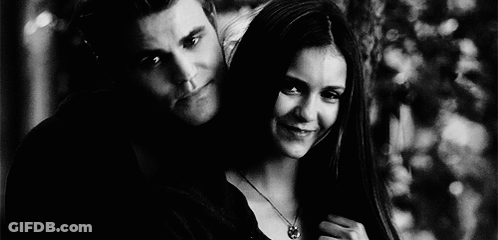 A Black And White Photo Of A Man And A Woman Standing Next To Each Other . GIF
