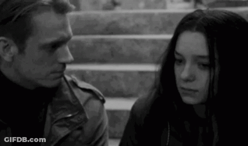 A Black And White Photo Of A Man And A Woman Standing Next To Each Other On Stairs . GIF