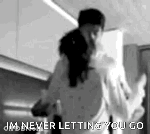 A Black And White Photo Of A Man And Woman Dancing In A Kitchen With The Words `` Im Never Letting You Go '' . GIF