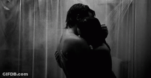 A Black And White Photo Of A Man And Woman Hugging Under A Shower Curtain . GIF