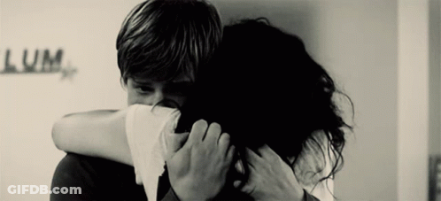 A Black And White Photo Of A Man And Woman Hugging With The Word Lum Written On The Wall Behind Them GIF