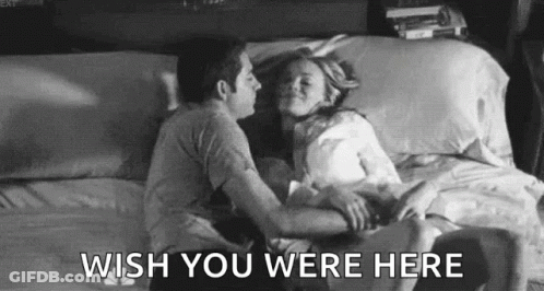 A Black And White Photo Of A Man And Woman Kissing On A Bed With The Words `` Wish You Were Here '' . GIF