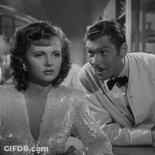 A Black And White Photo Of A Man And Woman Looking At Each Other GIF