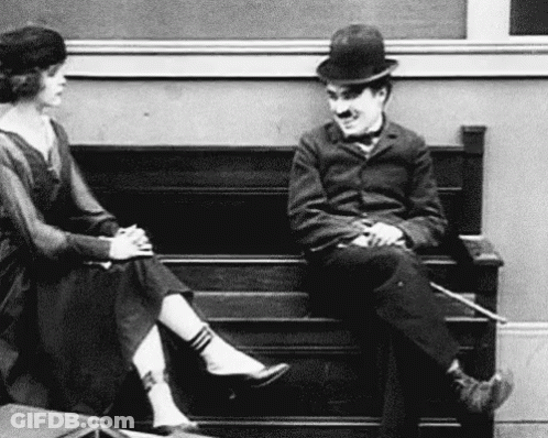 A Black And White Photo Of A Man And Woman Sitting On A Bench . GIF